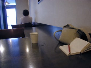 小さな鞄と赤鉛筆(休憩の途中)。背景に人物が一人写る