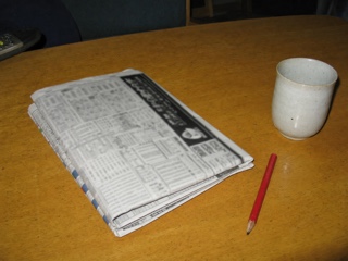 机に置いた折った新聞と赤鉛筆と湯のみ