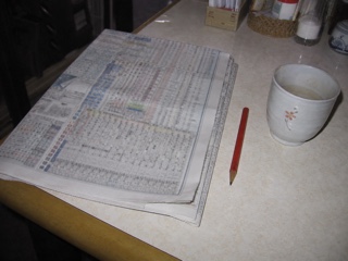 食卓の折った新聞と短い赤鉛筆と湯のみ