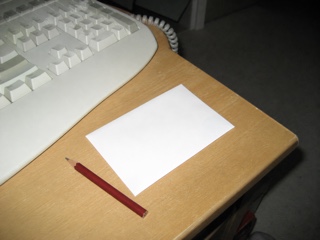 机の端の古いキーボードと赤鉛筆と白い封筒