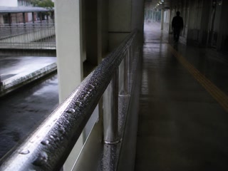雨粒の残る手すり(休憩の途中)。背景に人物が一人写る