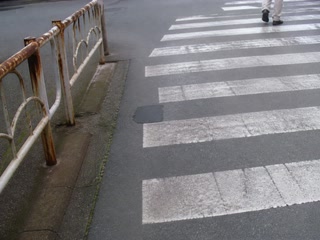 薄曇りの横断歩道(移動の途中)。背景に人物が一人写る