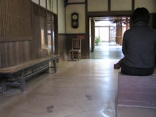 古い時計の下の椅子(休憩の途中)。背景に人物が一人写る