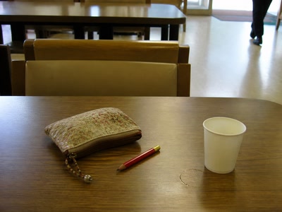 小さな鞄と赤鉛筆（帰り支度の前）。背景に人物が一人写る