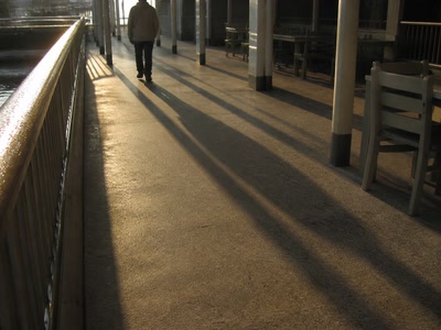 通路の床と長い影（帰り支度の前）。背景に人物が一人写る