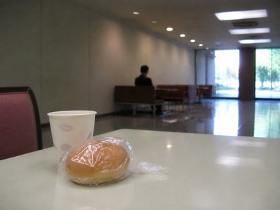 甘いパンと紙カップ（休憩の途中）。背景に人物が一人写る