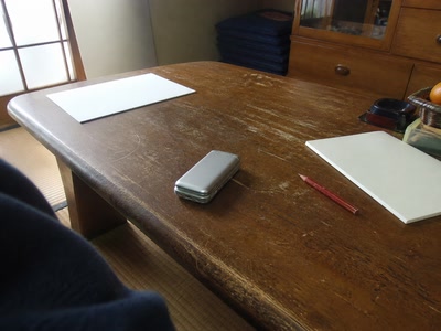 伏せた携帯電話と赤鉛筆（机へ座った時）
