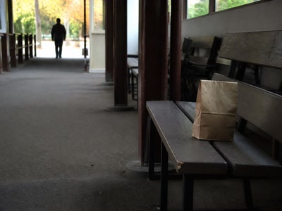折り目のついた紙袋（鞄を持ち直した時）。背景に人物が一人写る