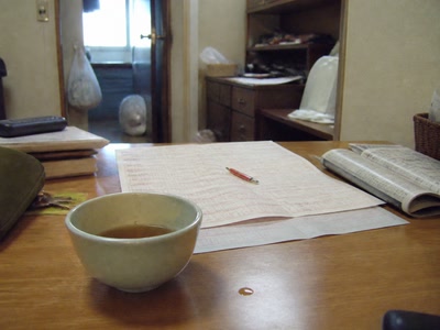 買い目の紙と冷めた茶（小銭をしまう途中）
