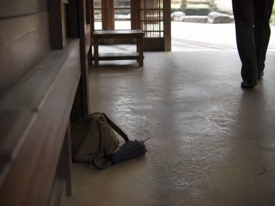 鞄の横の折り畳み傘（鞄を持ち直した時）。背景に人物が一人写る
