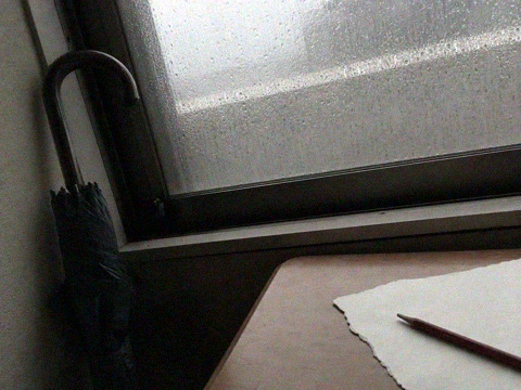 雨の窓と閉じた傘と机の赤鉛筆