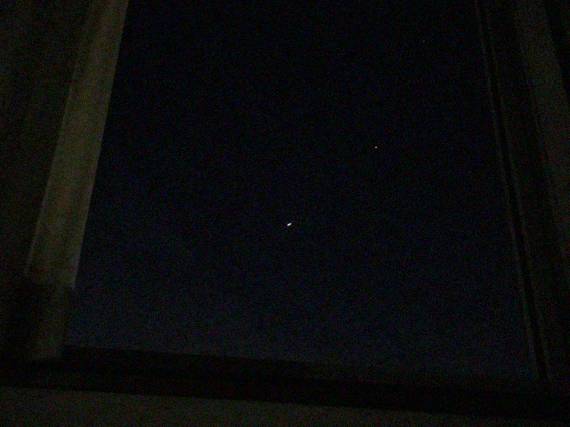 窓から見た暗い夏の夜空と小さな光
