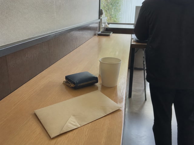 小銭入れと紙コップ（人の流れが切れた時）。背景に人物が一人写る