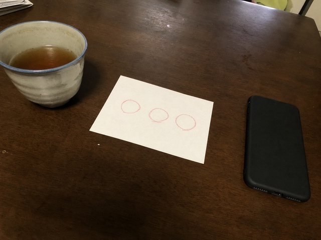 三つの赤い丸を書いた紙と伏せたスマートフォンと湯のみ