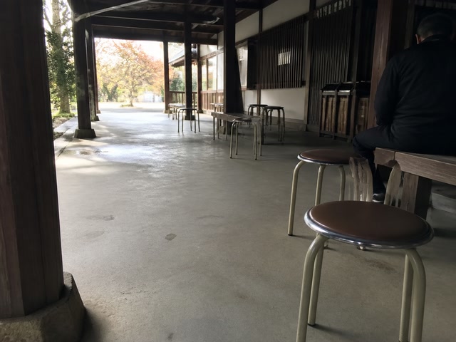 空いた丸椅子（人の流れが切れた時）。背景に人物が一人写る