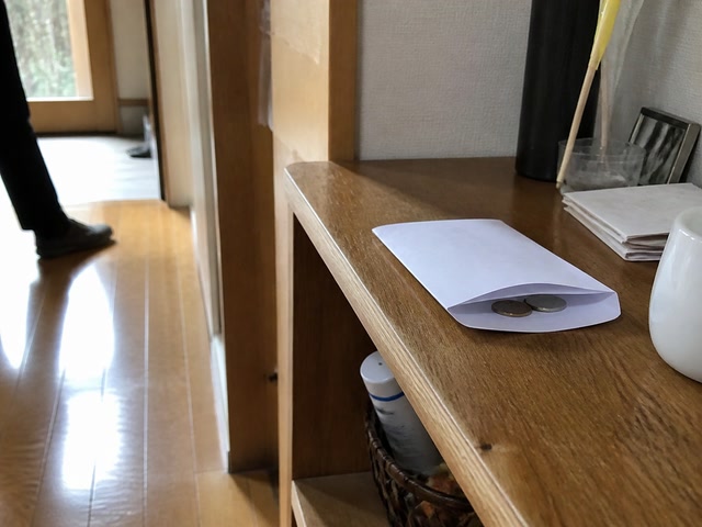 封筒に戻した小銭（人の流れが切れた時）。背景に人物が一人写る
