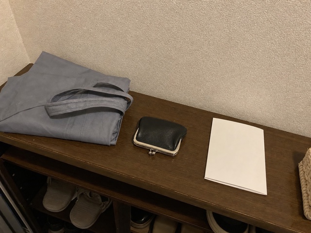 玄関の棚に置いた買い物袋と小銭入れと白い紙